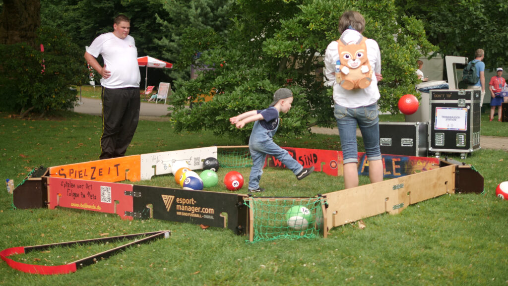 ein Junge spielt in der Ballbande mit seinen Eltern